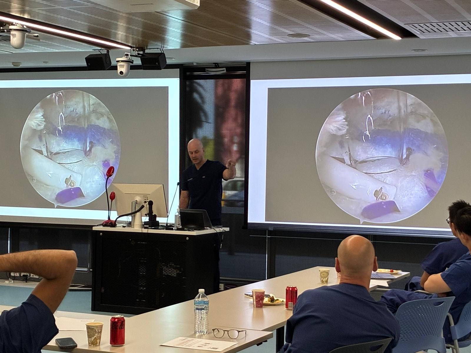 Dr Joe Coory presenting to shoulder fellows at the Fellows Shoulder Essentials Instructional Course, Macquarie University, Sydney, with an arthroscopic view on the screens
