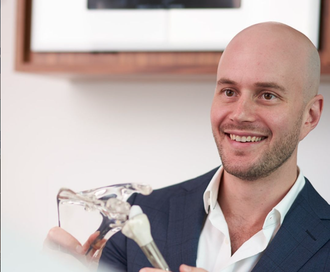 Dr Joe Coory holding a clear anatomical shoulder model with implant